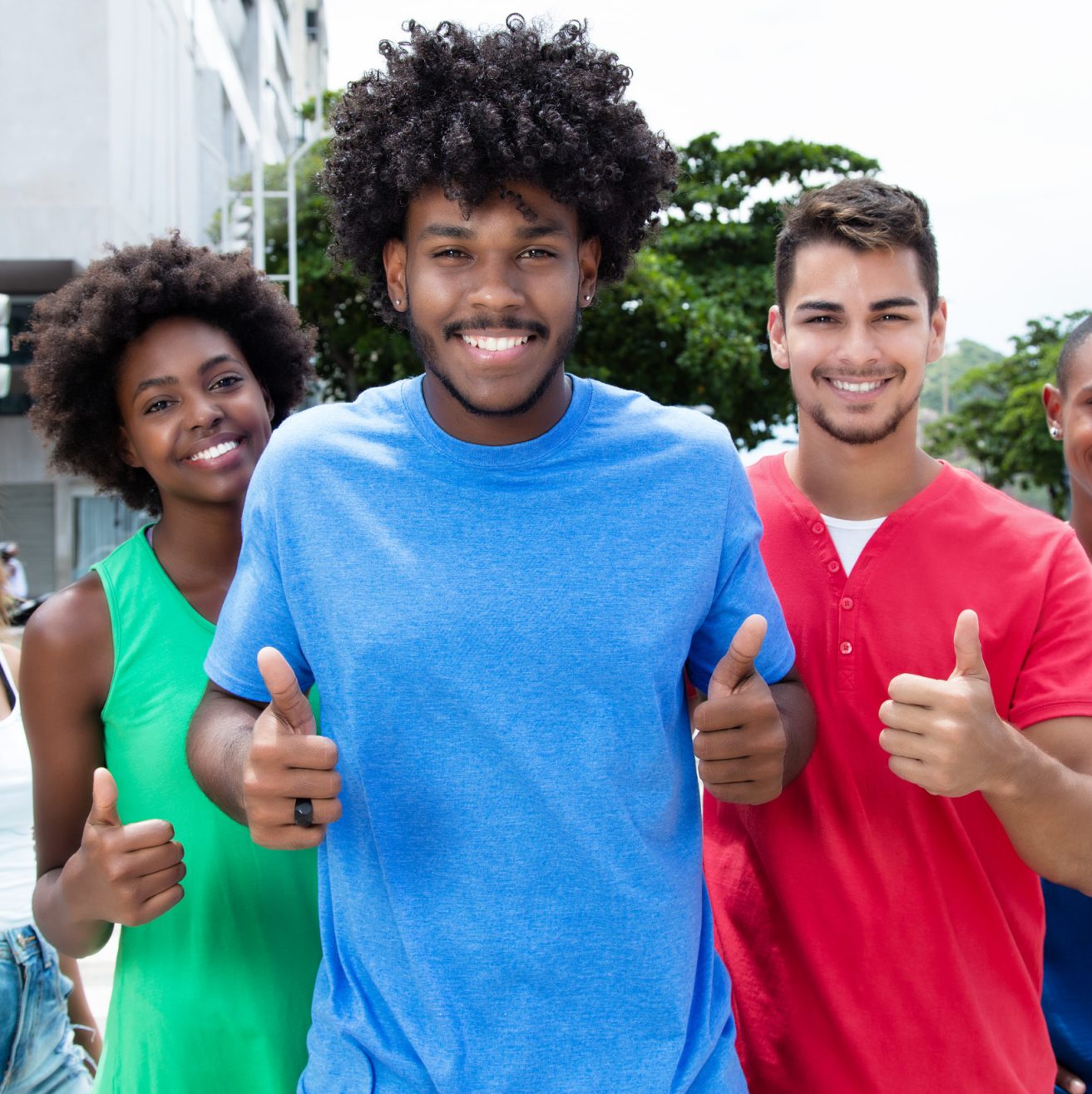 Group of international young adults showing thumbs in city